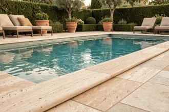 Margelles de piscine en pierre naturelle travertine entourant une piscine extérieure moderne avec jardin méditerranéen